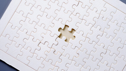 White puzzle with one missing piece on light background, symbolizing problem solving, teamwork, incomplete task, solution finding, and strategic thinking concept.
