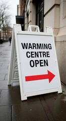 A warming centre open sign on a wet city sidewalk. Emergency shelter providing help and assistance for the homeless during cold winter weather.