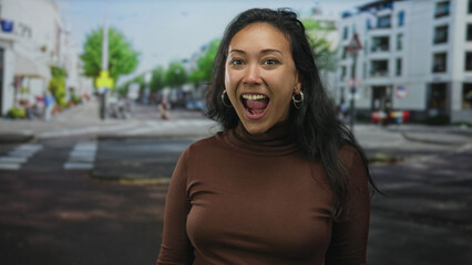 Woman laughing with open mouth looking up on street near crosswalk and storefronts in city; joy wonder.