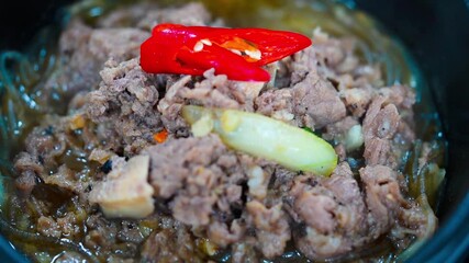 Sliced beef is added to a bubbling pot of so-bulgogi in a traditional ttukbaegi
