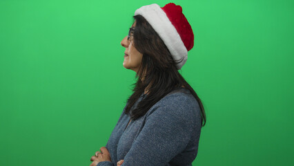 Middle age hispanic woman wearing glasses and santa hat with crossed arms in studio side profile; holiday rejection.