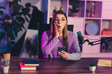 Charming female influencer surprised while working in a stylish home studio equipped with microphone and phone