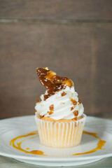 Delicious cupcake topped with cream, caramel sauce, and nuts