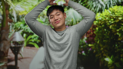 Young man smiling in a lush green park showcasing joyful expression in a tranquil outdoor setting with vibrant natural surroundings and casual fashion attire.