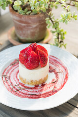 A delightful strawberry cheesecake on a white plate, beautifully presented. The red strawberries add a pop of color, making the dessert visually appealing