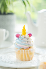 A delightful unicorn cupcake, adorned with colorful frosting and a golden horn, sitting on a plate
