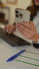 Woman using smartphone in office setting with keyboard calendar blue pen on desk in interior workspace showing hands phone technology indoors business modern