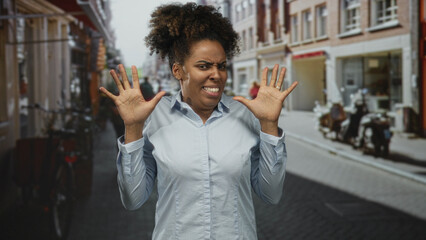 Woman with hands raised and grimacing on a street, palms splayed in a defensive gesture against a busy city lane; disgust avoidance.