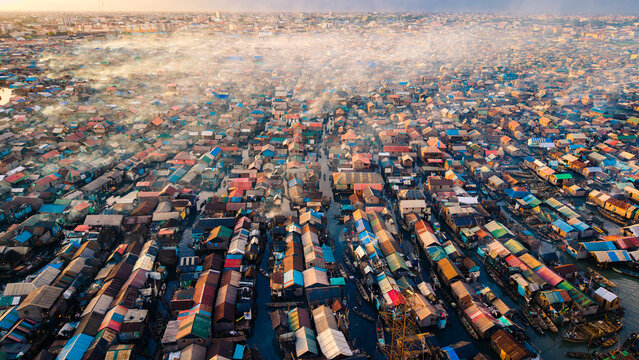 Aerial view of a sprawling settlement, where colorful rooftops nestle tightly together, intersected by waterways filled with boats, creating a vibrant tapestry of life, Lagos, Lagos, Nigeria.