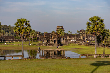 Fototapeta premium Angkor wat entrance pavilion and palm trees mirrored in the pond under soft morning light in siem reap, cambodia