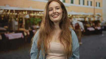 Woman smiling with face visible and long hair framing shoulders on restaurant terrace outdoors; contentment.