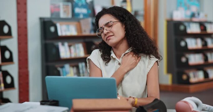 Woman, college student and shoulder pain at library with laptop, stress and fatigue for scholarship. Girl, injury and joint ache with inflammation, education and computer with research at university