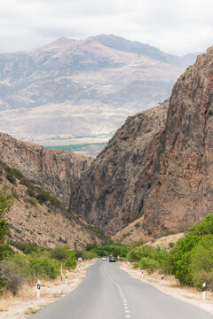 View of a long road stretching between towering cliffs under a vast sky, leading toward distant mountains, a serene journey, Magellan Cave, Vayots Dzor Province, Armenia.