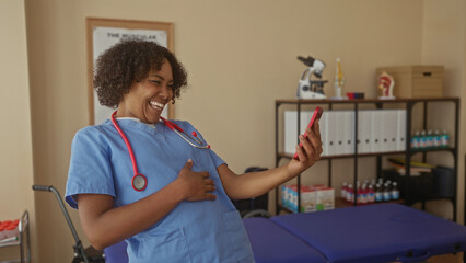 Woman doctor taps smartphone screen with finger while smiling in clinic evaluation room; digital connection joy.