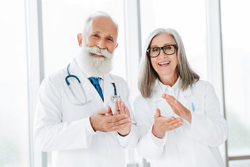 Cheerful doctors in white coats clap in a bright clinic celebrating teamwork patient care and...