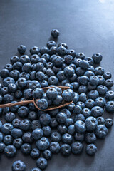 Bluecrop blueberries on a natural slate background and walnut wood spoon with pronounced grain