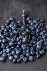 Perfectly ripe blueberries on a polished black marble background with a clear glass spoon revealing their juicy interior