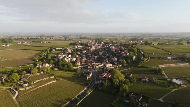 A gentle aerial approach &mdash; Saint-&Eacute;milion emerges among rolling green vineyards in the morning light.