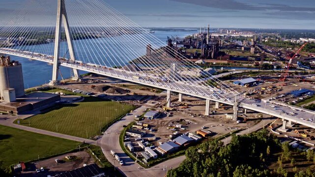 Drone shot flying over new gordie howe international bridge towards industrial landscape along detroit river