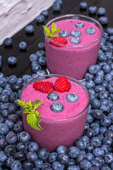 Composition with blueberries and a blueberry and green tea smoothie on a red cedar wood surface