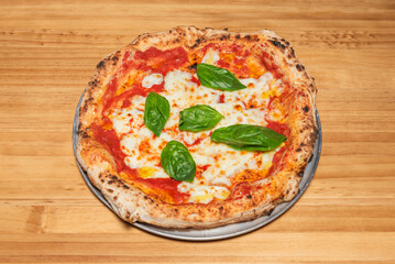 Freshly baked pizza with a crispy base, natural tomato sauce, fresh mozzarella, and aromatic, freshly picked basil over a wooden table