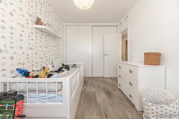 Teen bedroom with a bed with a padded headboard, study table with built-in light, and a swivel chair