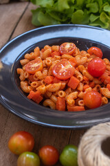 Classic macaroni and tomato sauce on a black plate.