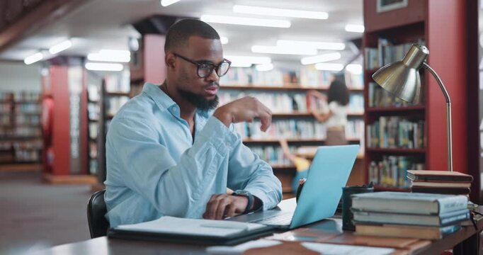 Student, laptop and typing in library with man for education, assignment or thesis on college campus. Technology, writing and male person with learning, preparation for exam or research for paper