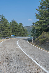 Fototapeta premium Mountain road with banked curves descends between terraces. Natural terraced vegetation and eroded rock formations