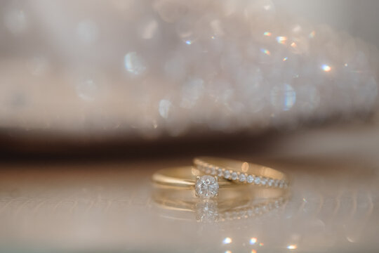 Goldene Eheringe mit Diamant auf glitzerndem Stoff &ndash; elegantes Hochzeitsdetail