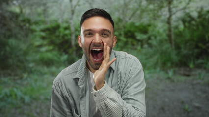 Hispanic man expressing surprise with open mouth and hands on face, outdoors in a green park...