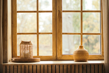 Close-up of a warm wooden window with decorative objects on the sill, offering a soft focus view of nature outside.