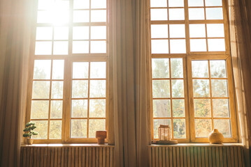 Sunlit cozy interior with wooden framed windows and warm curtains, overlooking autumn nature 