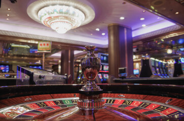 Teil von Spieltisch in Kasino auf Kreuzfahrtschiff mit Slotmaschinen im Hintergrund Glücksspiel -...