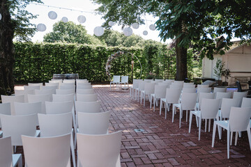 Hochzeitszeremonie im Freien mit Blumenkreis und weißen Stühlen