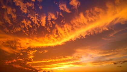 Fiery clouds ablaze at dusk, painting the sky in hues of orange, yellow, and blue during a vibrant sunset spectacle