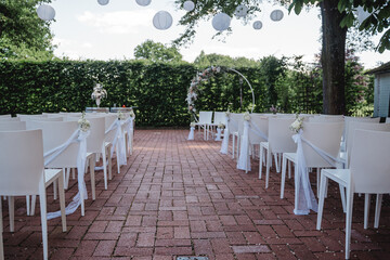 Hochzeitszeremonie im Freien mit Blumenkreis und weißen Stühlen