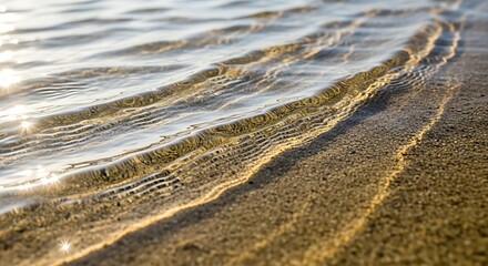 Gentle sunlit ripples creating patterns on the sand in shallow clear water.