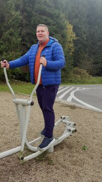 Young overweight man exercising on outdoor machine