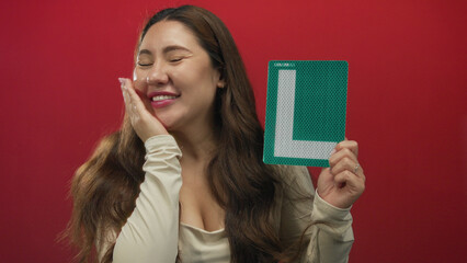 Young hispanic woman holds a green l plate and smiles in studio setting; confidence progress practice achievement.