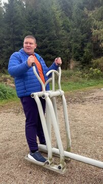 Young overweight man exercising on outdoor machine