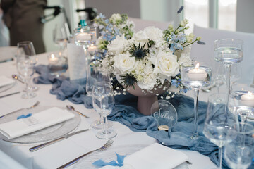 Elegante Hochzeitsdekoration mit weißen Blumen und blaugrauen Stoffen, festlich gedeckter Tisch im modernen Bankettsaal
