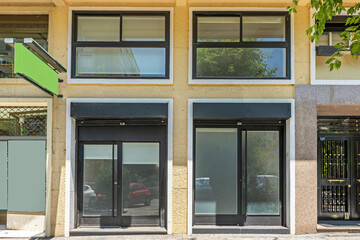 Modern facade of a small commercial space with a large floor-to-ceiling window that allows a view of the illuminated interior