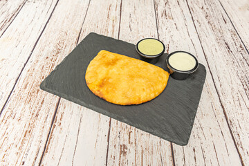Argentine humita empanadas with tomato and onion creole sauce, sprinkled with smoked paprika and fresh parsley