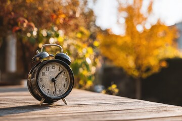 Fall Back One Hour. Daylight Saving Time Concept with Black Clock on Wood Background
