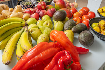 Modern still life where ripe bananas, juicy pears, ripe avocados, freshly picked potatoes, sweet nectarines, and fresh figs create chromatic contrast on a sky blue table