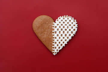 Decorated heart-shaped gingerbread cookie on a red background, copy space for text