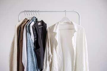 A wrinkled white shirt on a rail hanger from a light autumn capsule wardrobe. Copy-space mockup.