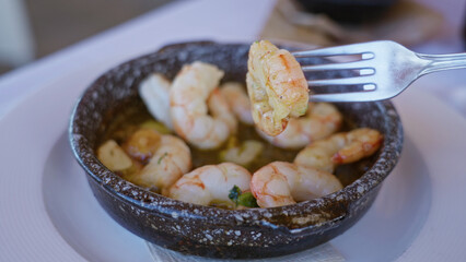 Delicious shrimp in a rustic bowl served with garlic at a mediterranean restaurant, showcasing vibrant indoor dining ambiance.