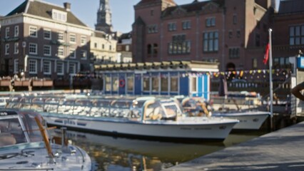 Defocused scene of amsterdam canals with boats and historic buildings in bright sunlight showcasing...